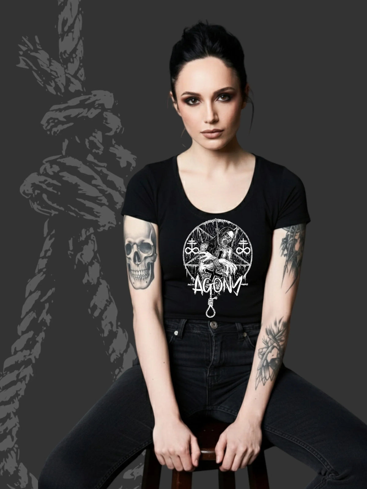 Femme tatouée en t-shirt noir Agony Clothing, style alternatif sombre, fond corde noire.