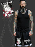 Homme tatoué portant un short Agony Clothing avec motif graphique sombre et texte « The pain is in the head ».