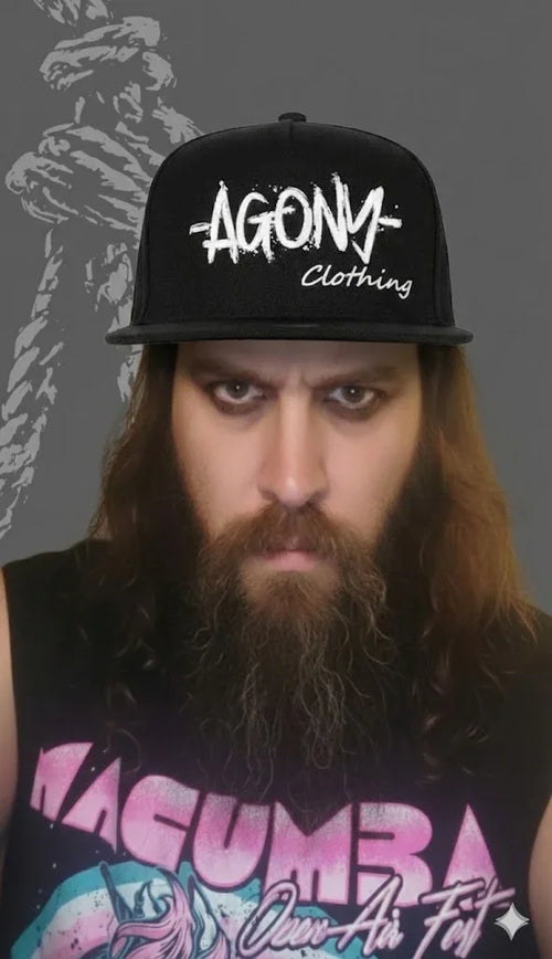 Homme barbu portant une casquette Agony Clothing, look alternatif, streetwear sombre.